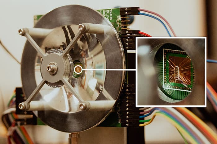 تصویر 1. سامانه تصویرساز تراهرتزی، یک ریزتراشه (جزئی که در تصویر بزرگنمایی شده است) و یک بازتابگر دارد که بُرد و کیفیت تصویرسازی را افزایش و مصرف برق آنرا کاهش میدهد. ریزتراشه از پیکسلهای ریز خود، پرتوهای تراهرتزی با بسامد 430 گیگاهرتز منتشر میکند. این پرتوها از موانعی مثل مه و برف و دود که نور مرئی نمیتواند در آنها نفوذ کند، میگذرد. پرتوها پس از برخورد با اجسام پشت مانع از آنها منعکس میشوند و به ریزتراشه بازمیگردند. پیکسلهای ریزتراشه، با پردازش علائم دریافتی، تصویر میسازند. (تصویر از وبگاه دانشگاه تگزاس، دالاس)