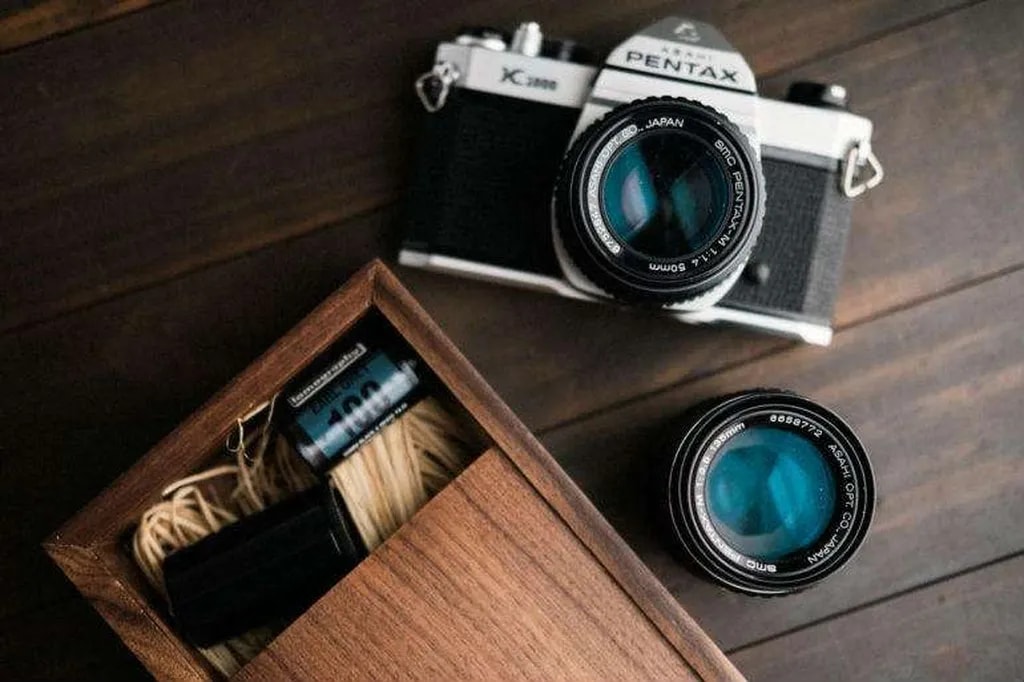 دوربین دوستداشتنی Pentax K1000 و یک حلقه فیلم 135 با حساسیت 100 در کنار آن